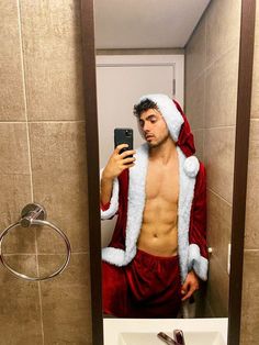 a man dressed as santa claus taking a selfie in the bathroom