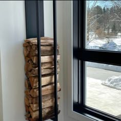 a stack of firewood sitting next to a window in a room filled with snow