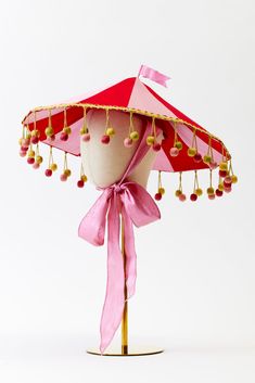 a pink and red umbrella with tassels attached to it's sides on a stand