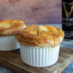 two small pies sitting on top of a wooden cutting board next to a bottle of wine