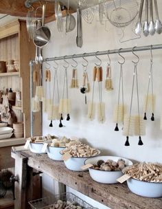 several bowls and spoons on a table in a room with hanging utensils