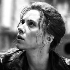 a black and white photo of a woman wearing a leather jacket looking off into the distance