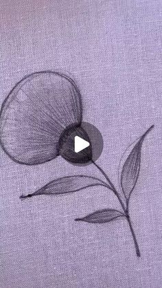 a drawing of a flower on a piece of cloth with a video playing button in the middle