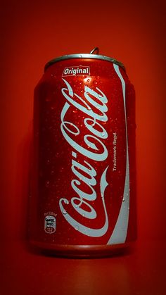 a can of coca - cola on a red background