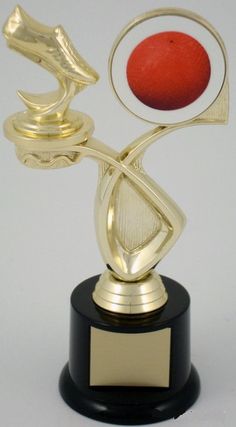 a gold trophy with a red ball on it's end and a black base