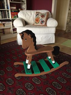 a wooden rocking horse sitting on top of a red rug in front of a white chair