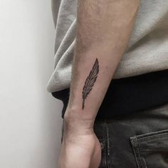 a man with a small feather tattoo on his arm