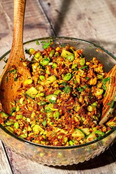 a wooden spoon in a glass bowl filled with food on top of a wooden table