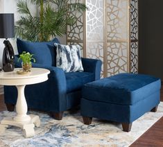 a blue chair and ottoman in a living room next to a table with a potted plant on it