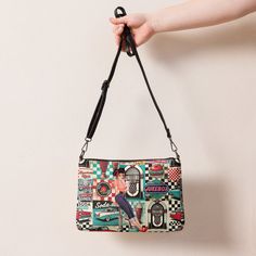 Take a trip down memory lane with our Retro Diner Pin-Up Crossbody Bag. This vintage 50s Rock n’ Roll Jukebox design is the perfect accessory for any classic American diner lover. With its retro style and practicality, it's a must-have for your wardrobe. Crafted from premium faux leather with sleek dark gray hardware, this crossbody bag ensures your essentials stay secure and organized with its zip-top closure and multiple interior pockets. Easily switch between day-to-night looks using the removable wrist and shoulder straps for versatile styling.• Outer fabric: faux leather • Lining: 100% polyester• 11″ × 8″ × 1.5″ (27.9 cm × 20.3 cm × 3.8 cm)• Dark gray hardware• Zip-top closure• Inside zip and slip pockets• Adjustable, removable wrist and shoulder straps• Strap drop length: 14″- 27″Thi Classic American Diner, 50s Rock And Roll, American Diner, Retro Diner, Classic American, Rock N, Rock N Roll, Diner, Pin Up