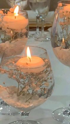 candles are lit in glass vases on a table