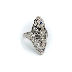 This is part of Chairish’s Fine Jewelry assortment.  This is a stunning Art Deco navette-shaped 18 karat white gold, diamond and sapphire ring. The ring has some excellent filigree work that merges organic abstract shaped with sharp angular lines.   The centre diamond measures 3.35 mm, and the diamonds flanking the centre diamond are 3 mm each, for a total carat weight of approximately .5 carat. The diamonds are three Old European Cuts with high tables. The diamonds are set in octagon shapes. Ab Elegant Marquise Ring With Intricate Design, Marquise White Gold Sapphire Ring, White Gold Marquise Sapphire Ring, Marquise Platinum Gemstone Rings, Marquise Gemstone Platinum Rings, Exquisite Marquise Single Cut Diamond Ring, Exquisite Marquise Ring With Single Cut Diamonds, Exquisite Marquise Rings With Single Cut Diamonds, Marquise Diamond Cut Sapphire Ring