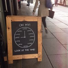 a sign that is on the side of a building with people walking by it and some buildings in the background