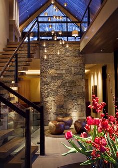 the interior of a modern house with stone walls and glass ceiling, flowers in vases on the table