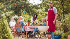 a group of people sitting around a bbq grill in the middle of a garden