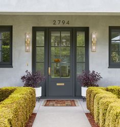 the front door of a house with two large hedges