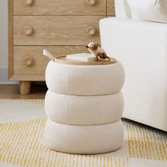 a white ottoman sitting on top of a rug next to a wooden dresser and bed