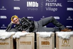 a man laying on top of wooden crates in front of a blue wall with white fur