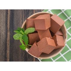 a wooden bowl filled with chocolate cubes on top of a green napkin