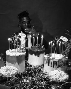 a man sitting in front of a table filled with cakes