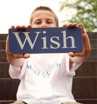 a young boy holding up a sign that says wish