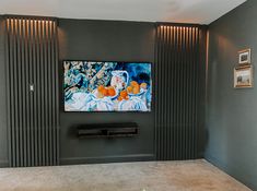 a flat screen tv mounted to the side of a wall in a living room with grey walls