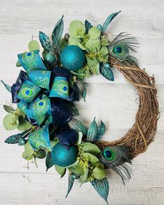 a wreath with blue and green decorations on top of a white wooden table next to a wall