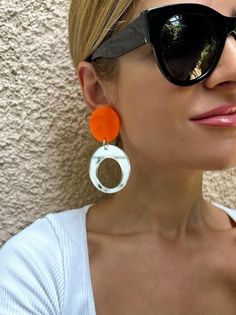 A Pair of Hoop Earrings that are made from Plexiglass and they open and close with Clip On. I used summer colors and the upper part is in orange color and the down hoop is made in a unique silver mirror color that smells summerThis pair is ideal for non pierced ears, they are comfortable and light.  Find them only at Chrstina Christi Store. MATERIALS - Plexiglass Parts. - Metal Parts. DIMENSIONS - Total length of Earrings: 9 cm (3.5') - Total width of Earrings: 3.5 cm (1.35') PROTECTION - Protec Modern White Clip-on Earrings, Hypoallergenic White Circular Earrings, Hypoallergenic White Circle Earrings, Modern Clear Dangle Earrings, Modern White Clip-on Earrings For Gift, Trendy White Drop Clip-on Earrings, Trendy Orange Round Earrings, Modern Handmade Clear Earrings, Trendy White Small Hoop Earrings