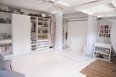 a living room filled with furniture and lots of white shelves next to a doorway that leads into a bedroom