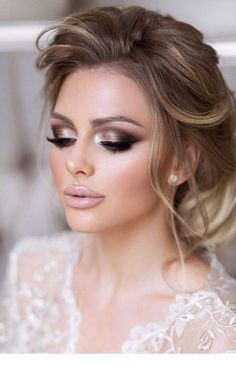 a woman with long hair and makeup looks down at her face, while wearing a white dress