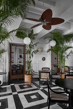 an indoor dining area with black and white checkered flooring, potted plants and ceiling fans