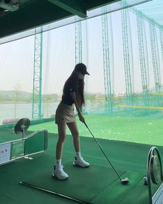 a woman is playing golf on a green course with water in the backgroud