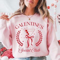 a woman wearing a pink valentine's social club sweatshirt with a martini on it