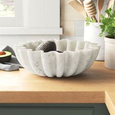 an assortment of fruits and vegetables are displayed on a countertop in the kitchen, along with utensils