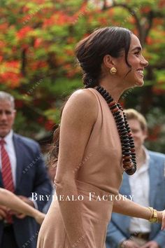 a woman in a tan dress is walking with other people