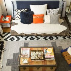 a living room filled with furniture and pillows on top of a rug next to a coffee table