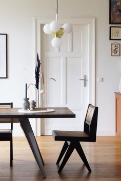 a dining room table with two chairs and a vase on the table next to it