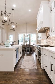 a large kitchen with white cabinets and wood flooring, along with an area rug on the hardwood floor