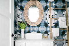 a white sink sitting under a bathroom mirror next to a wooden ladder and towel rack