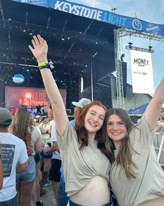 two young women standing next to each other at a music festival