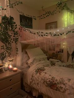 an unmade bed in a bedroom with plants hanging from the ceiling and candles on the floor