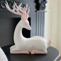 a white deer figurine sitting on top of a table next to a fireplace