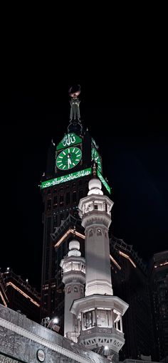 a clock tower lit up at night with lights on it's sides and the sky in the background