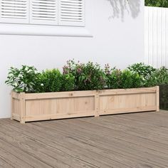 a wooden planter filled with green plants on top of a hard wood floor next to a white wall