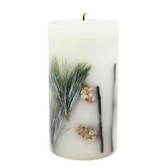 a white candle with pine cones and leaves on it