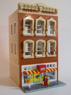 a toy building with a store front and windows on the outside, as well as a flower pot