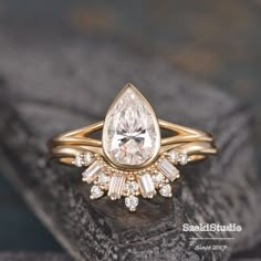 a gold ring with a pear shaped diamond surrounded by smaller round and baguette cut diamonds