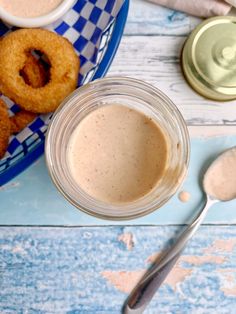 a glass jar filled with liquid next to some doughnuts on a blue and white plate