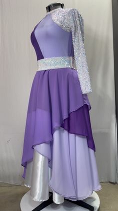 a purple and silver dress with sequins on the top is displayed in front of a white wall