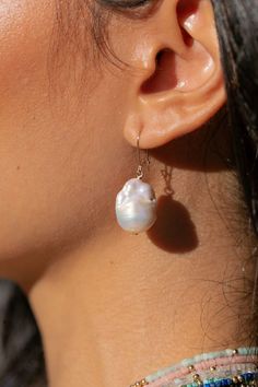 Complete your look with understated elegance. These white pearl earrings will be your new favorite adornments. Inspired by the ocean's treasures and our endless summers, these will bring the aloha breeze straight to your doorstep. ✦ Available in two Pearl Sizes - Manelle is wearing size Large ✦ ✦ DETAILS ✦✧ Name: Kiele (key AY lay) - fragrant blossom.✧ 14kt Gold Filled.✧ Small Baroque Freshwater Pearls; Large Baroque Flameball Pearls✧ Total Drop Length: Small - 27mm, Large - 35mm. ✧ Sold as a Pa White Pearl Jewelry, Pearl Statement Earrings, White Pearl Earring, Minimal Earrings, Baroque Pearl Earrings, Gold Pearl Earrings, Pearl Collection, Freshwater Pearls Earrings, Shell Jewelry